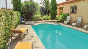 Una piscina con sillas de descanso y una terraza de madera.