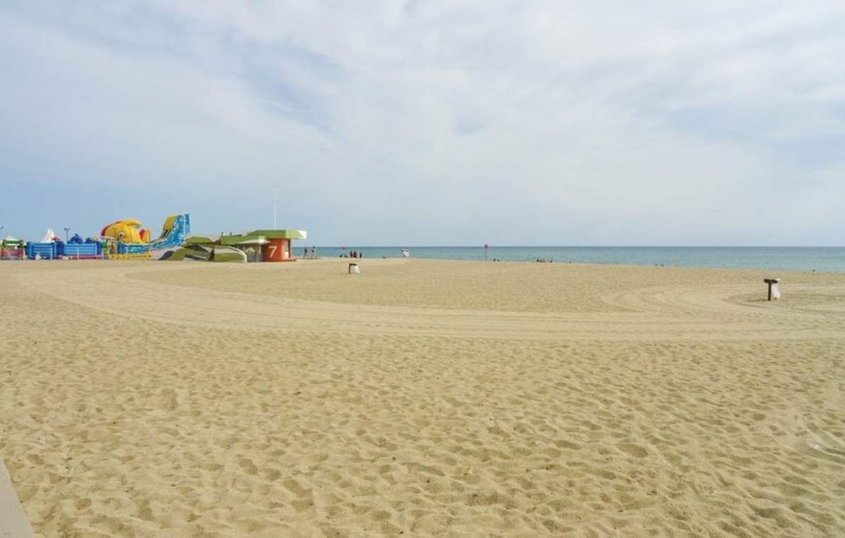 A sandy beach with a lifeguard tower and a colorful inflatable structure.