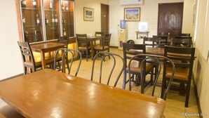 A dining area with wooden tables and chairs, a wine display cabinet, and a water cooler. - Isabelle Garden Hotel and Suites (Parañaque)