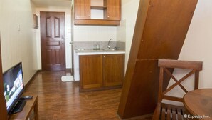 A compact kitchen with wooden cabinets, a built-in sink, and a television in the corner. - Isabelle Garden Hotel and Suites (Parañaque)