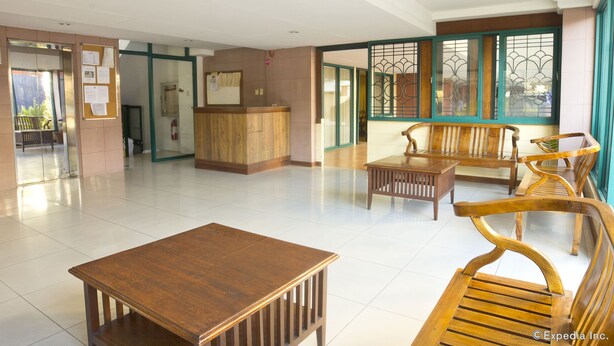A spacious lobby with a reception desk, wooden benches, and a small table. - Isabelle Garden Hotel and Suites (Parañaque)