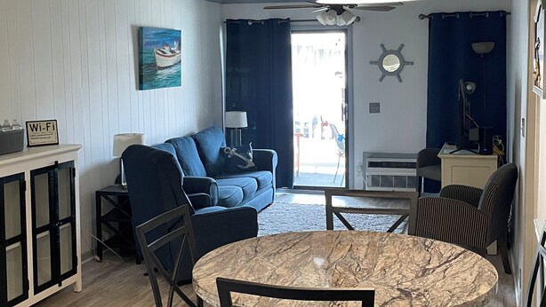 Ein Wohnzimmer mit einem blauen Sofa, einem runden Marmortisch und einem Deckenventilator.