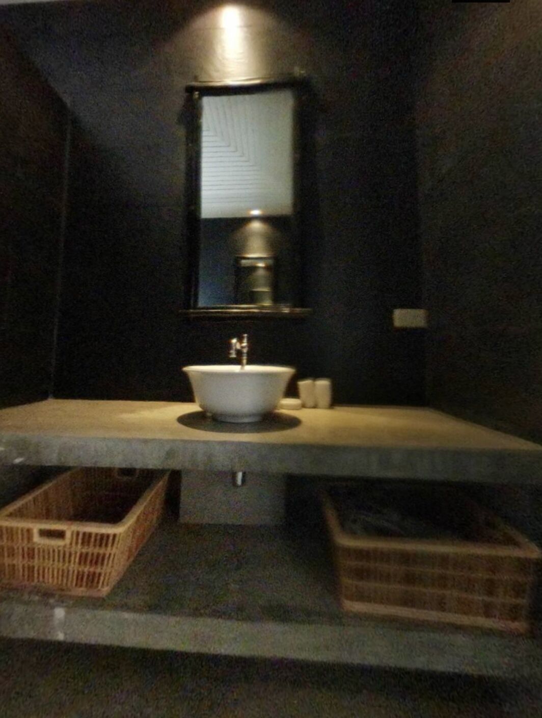 A bathroom with a white sink, a mirror, and two wicker baskets on the counter.