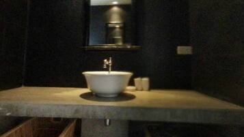 A bathroom with a white sink, a mirror, and two wicker baskets on the counter.