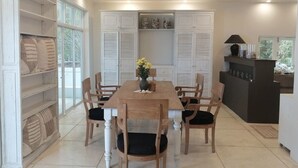 Un comedor con una mesa y sillas de madera, un ventilador de techo y una cocina con armarios y una encimera.
