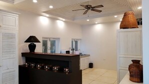 Una cocina moderna con una isla central, muebles blancos y un ventilador de techo.