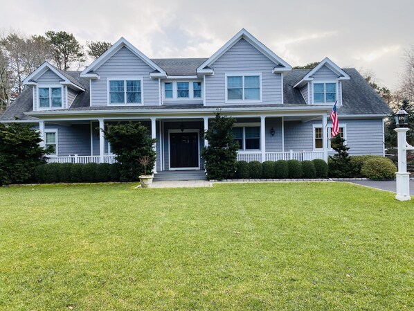 Classic two-story home with a symmetrical facade, featuring a central entrance and a small porch.