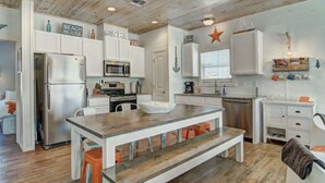 A modern kitchen with white cabinetry, a wooden island, and a star decoration on the wall. - Beach Please- Family Friendly | Community Pool (Port Aransas)