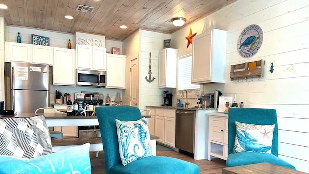 A modern kitchen with white cabinets, stainless steel appliances, and a starfish decoration on the wall. - Beach Please- Family Friendly | Community Pool (Port Aransas)