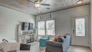 A living room with a white sofa, a gray sofa, and a white armchair. There is a TV on the wall and a fireplace. - Beach Please- Family Friendly | Community Pool (Port Aransas)