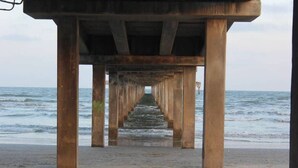 A pier extending into the sea with a clear view of the ocean. - Beach Please- Family Friendly | Community Pool (Port Aransas)