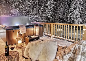 Relax in the serene hot tub surrounded by snow-covered trees.