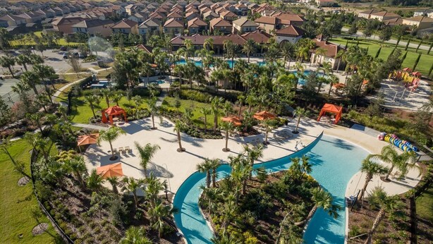 Vue aérienne d’un complexe hôtelier doté d’une grande piscine, de palmiers et de différents bâtiments.