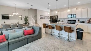 Une cuisine moderne avec des meubles blancs, un réfrigérateur noir et un coin bar équipé de tabourets.