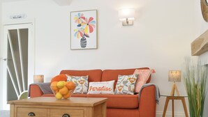 Una sala de estar acogedora con una mesa de centro de madera, un sofá naranja y cojines decorativos.