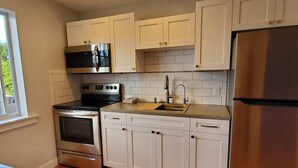 A kitchen with white cabinets, stainless steel appliances, and a window.