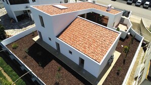 A modern building with a tiled roof, multiple balconies, and a paved ground area with small plants. - Brand New Villa with Private Pool and Lovely Garden near the beach.
 (Alvor)