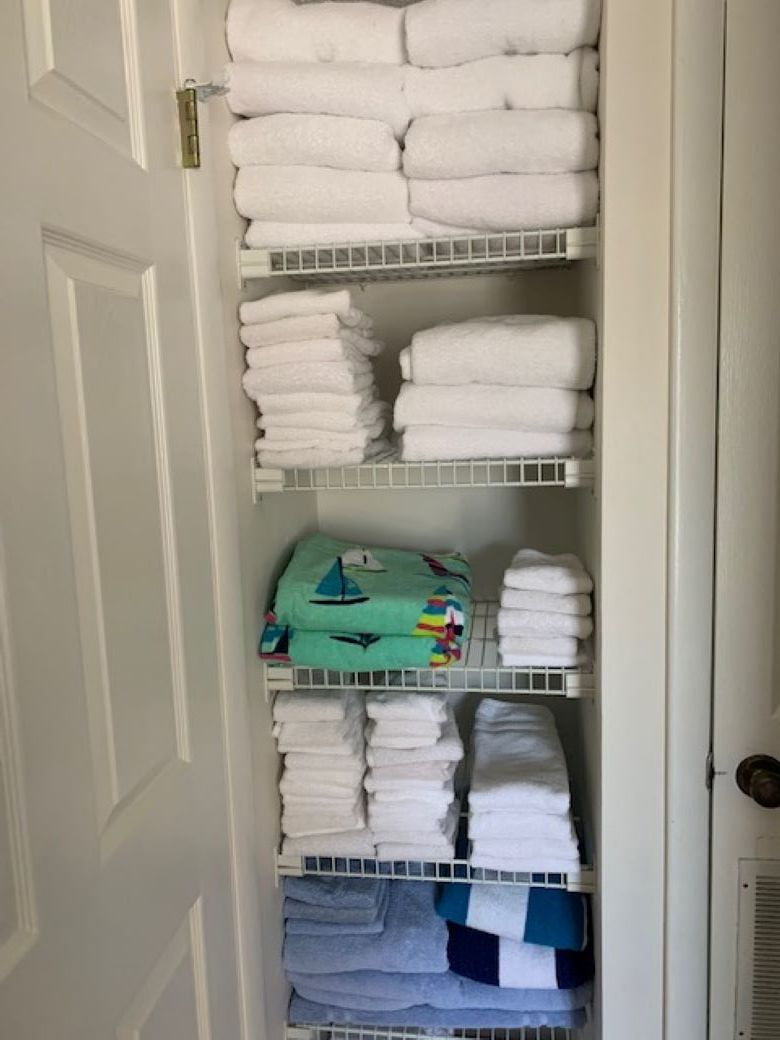A closet with multiple shelves holding folded towels in various colors.