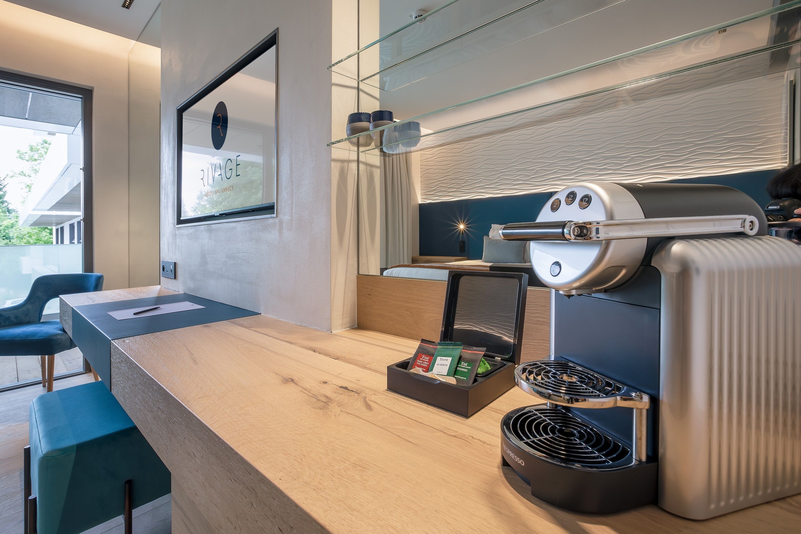 Une chambre d’hôtel moderne équipée d’un bureau en bois, d’une machine à café et d’un mini-bar.