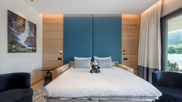 A modern bedroom with a large bed, two pillows, a nightstand, a small table, and a large window with curtains.
