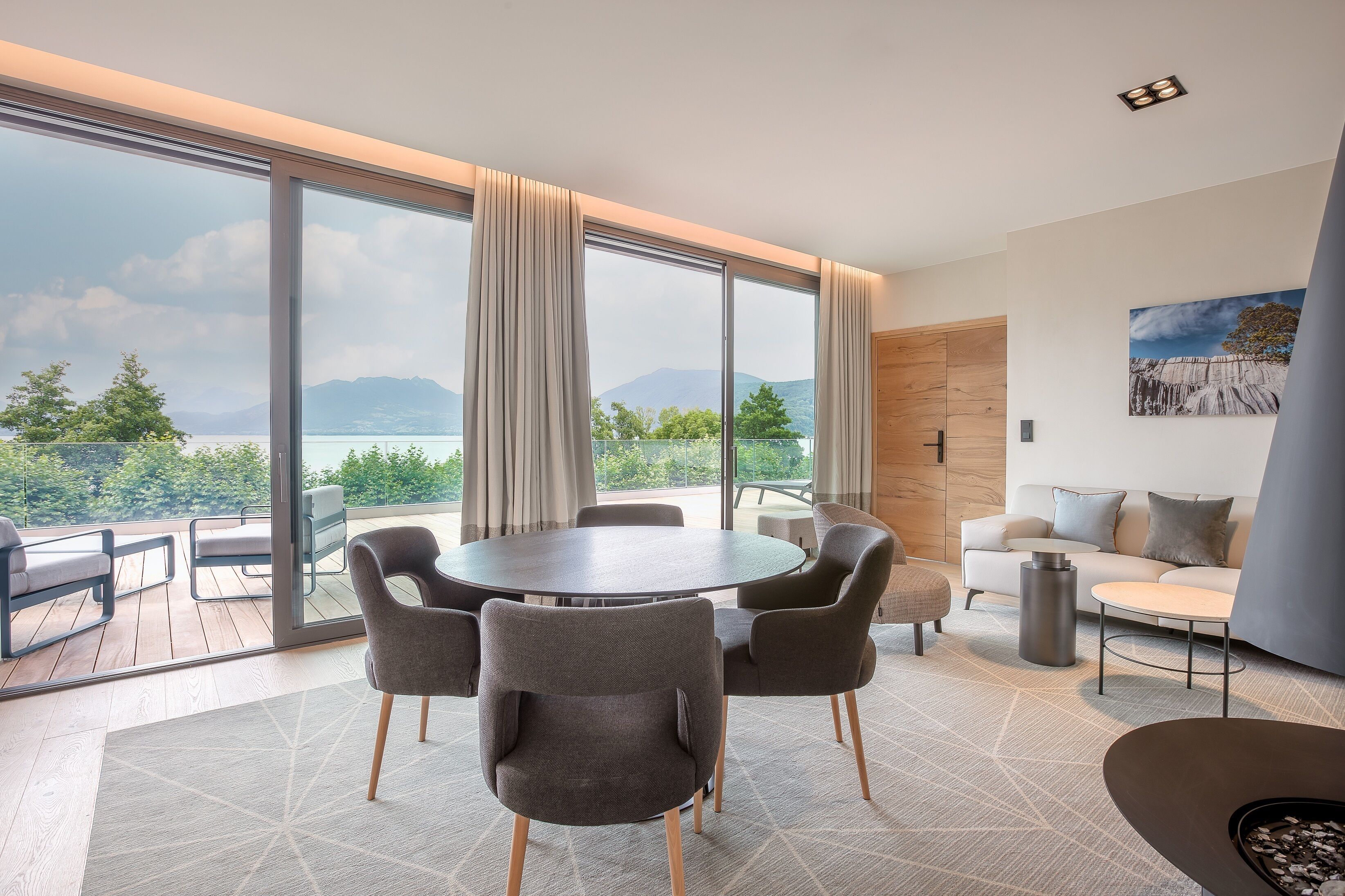 A modern living room with a large window, a round dining table, and a sofa.