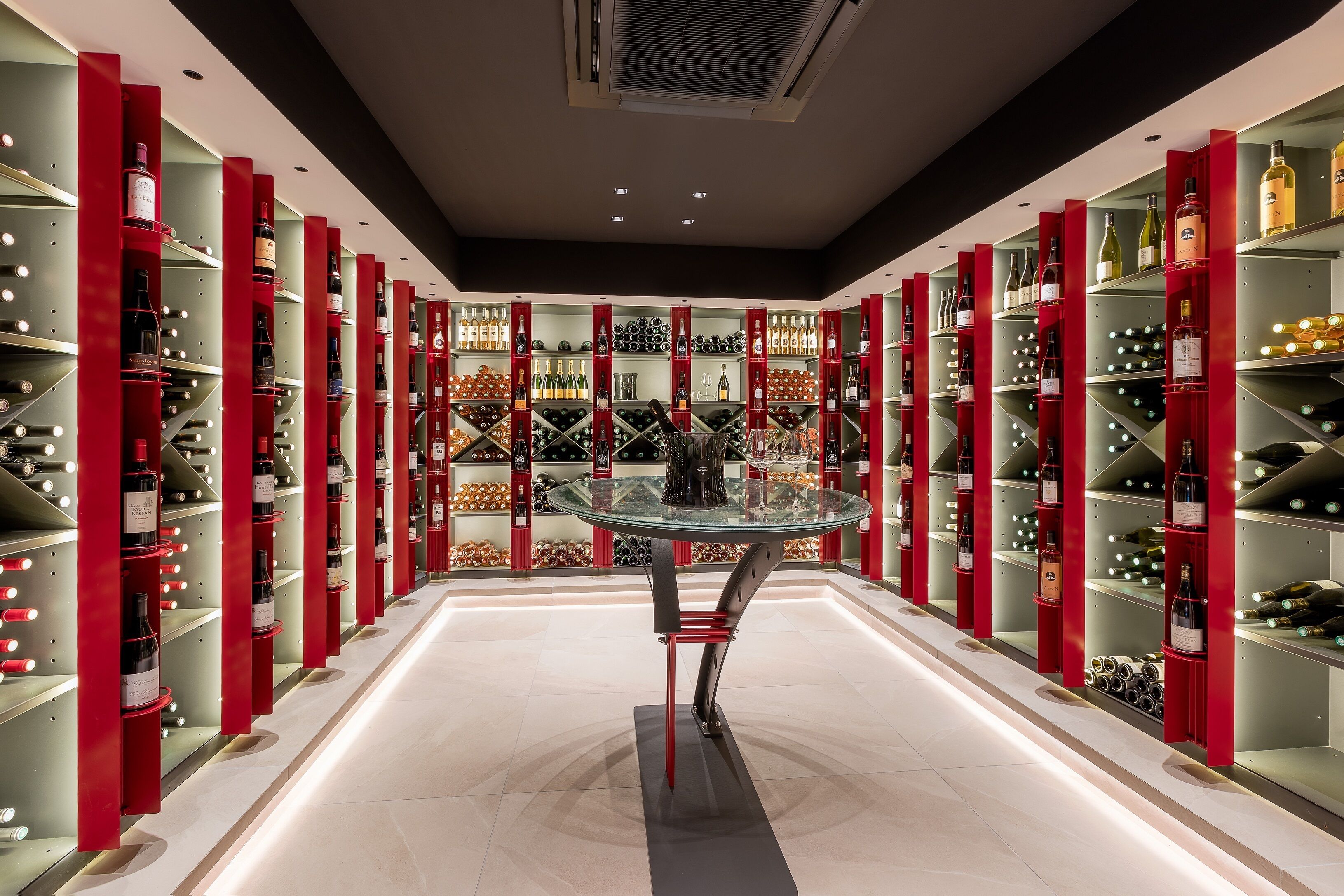 A wine cellar with shelves of wine bottles and a glass table in the center.