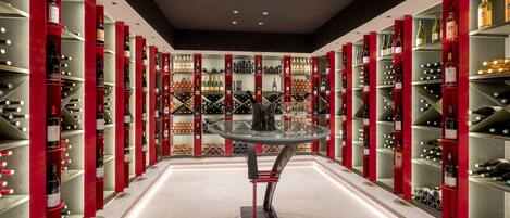 A wine cellar with shelves of wine bottles and a glass table in the center.