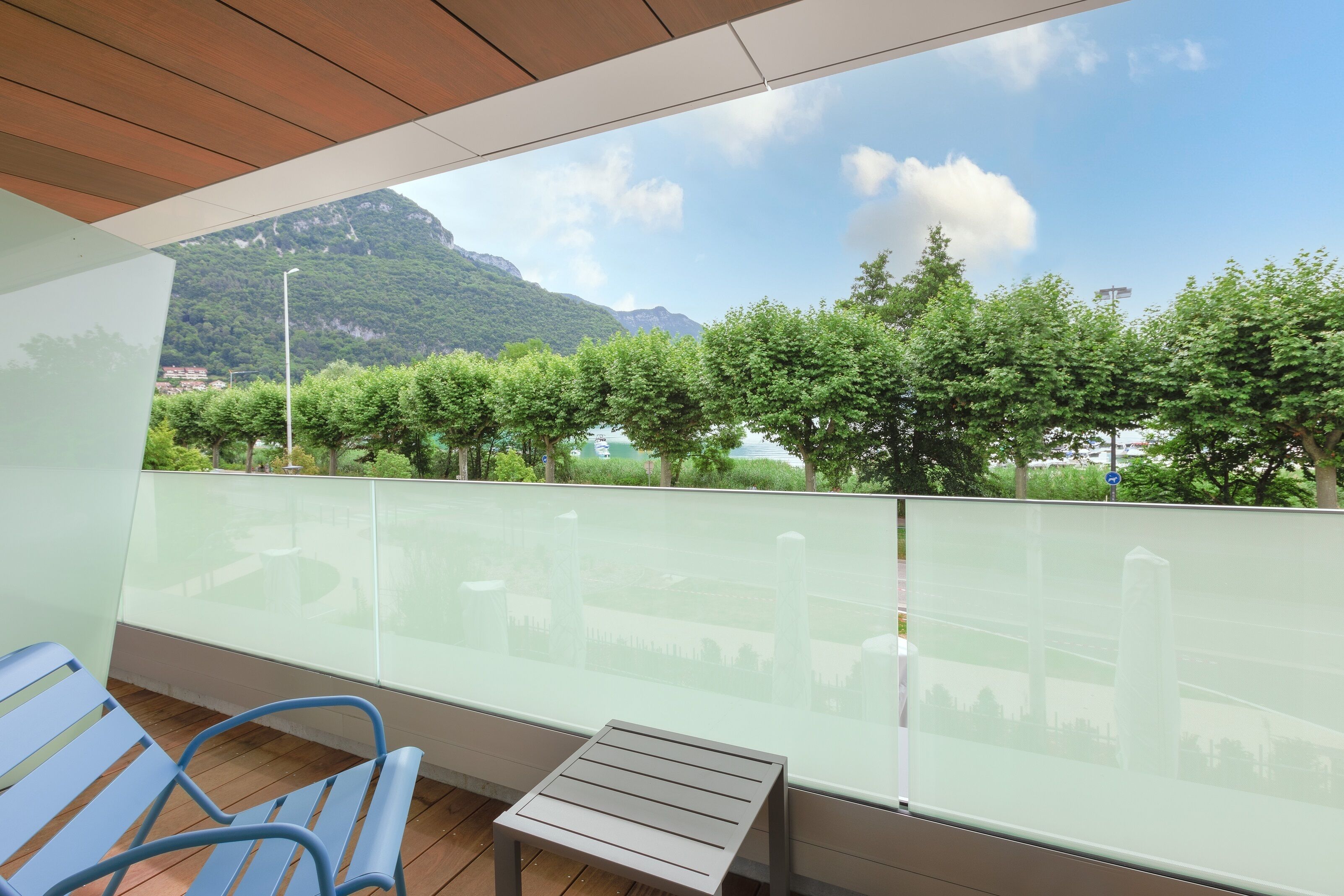 A balcony with a view of a mountain, trees, and a body of water.