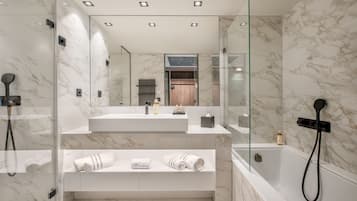 Une salle de bain moderne avec un mur en marbre, une douche en verre, un lavabo intégré et un meuble-lavabo avec des serviettes.
