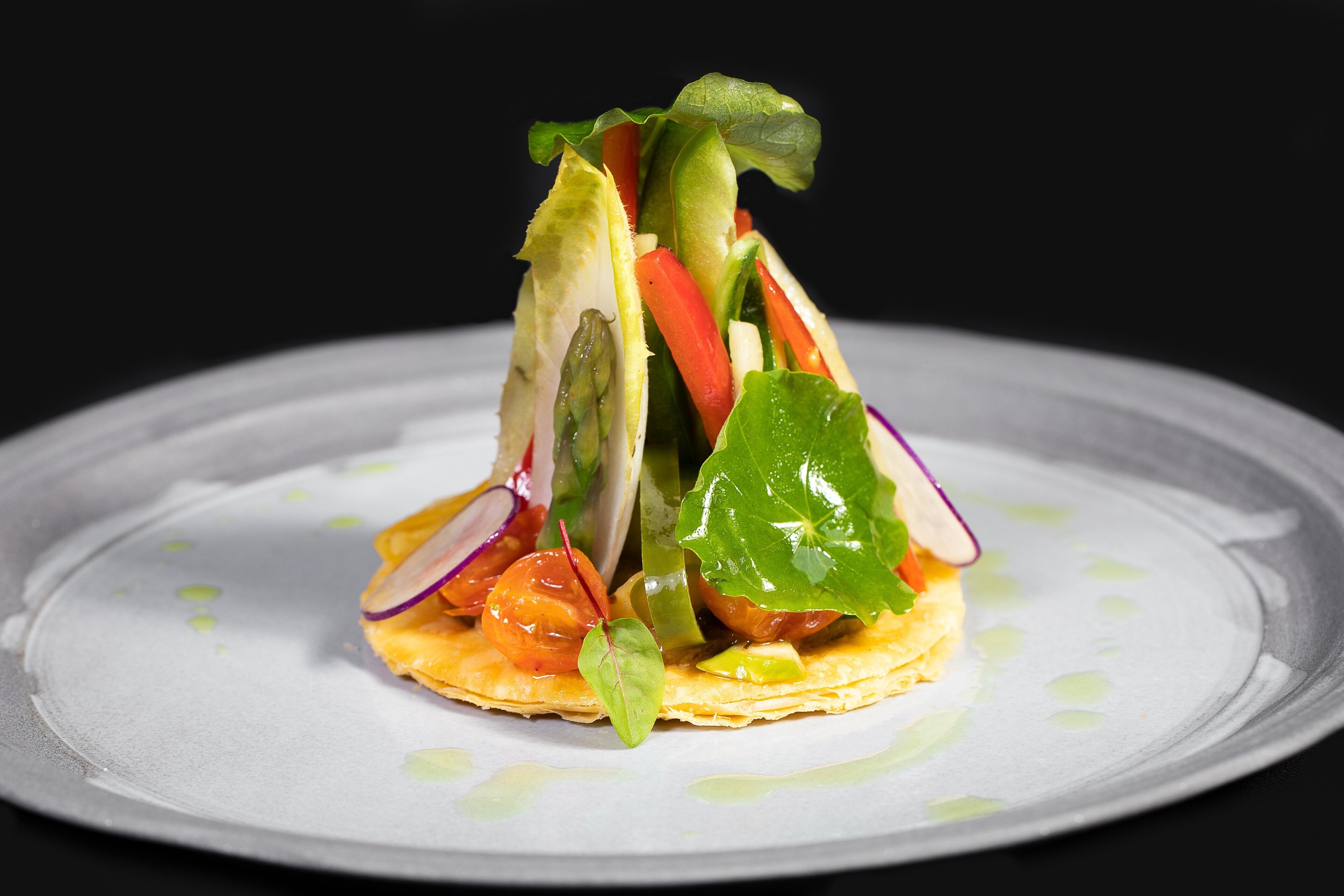 Un plato con diversos vegetales y un trozo pequeño de carne.