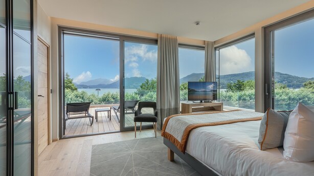 Une chambre moderne avec un grand lit, une télévision et un balcon offrant une vue sur les montagnes.