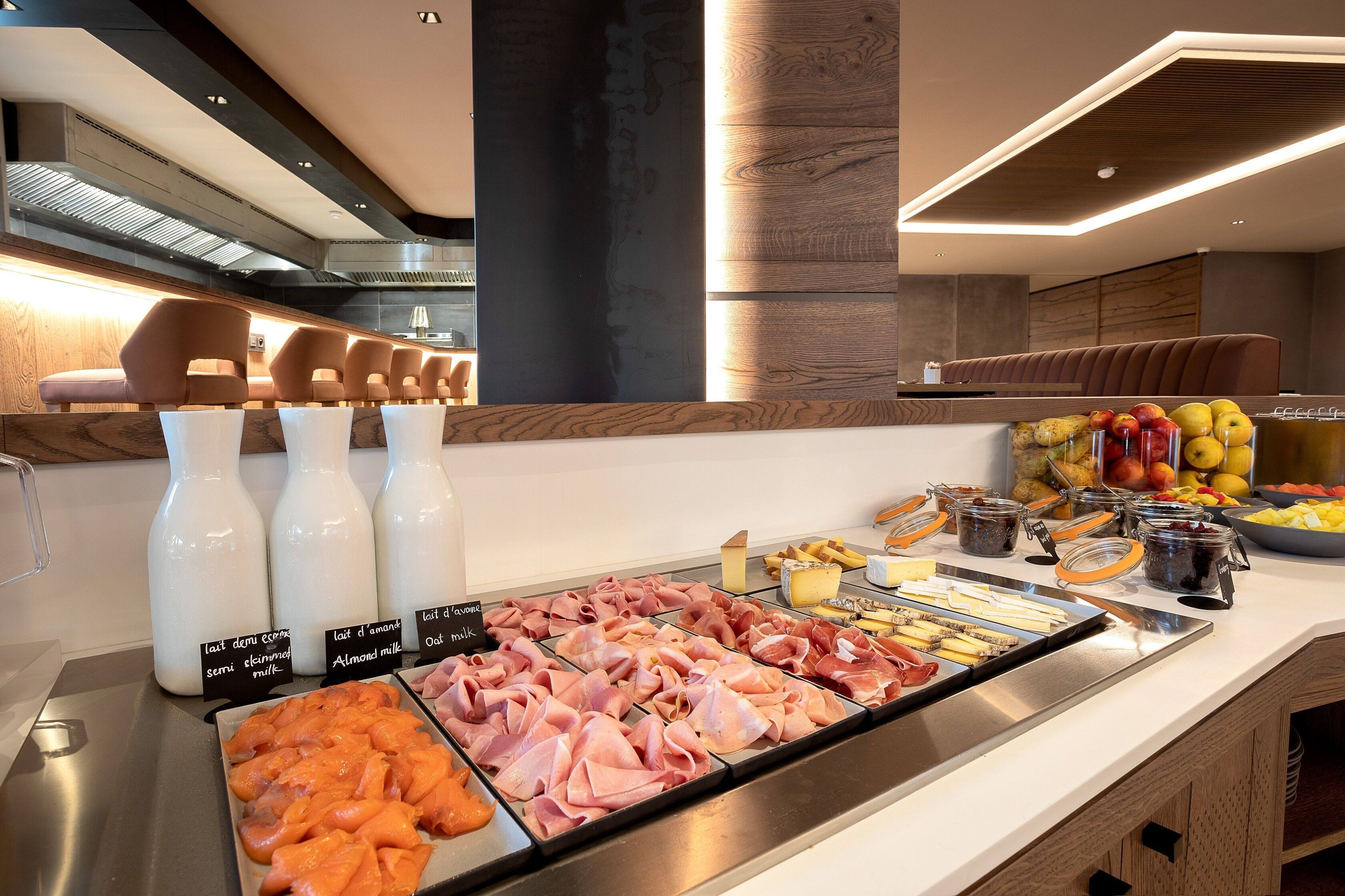 A buffet with various food options including meats, cheeses, and fruits.