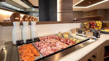 Un bufé con diversas opciones de comida, incluyendo carnes, quesos y frutas.