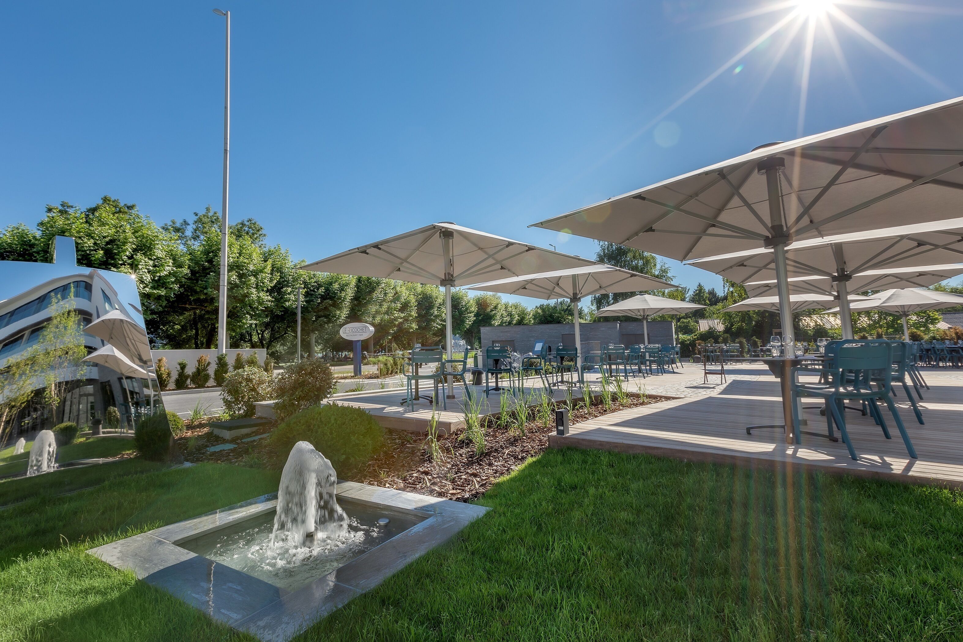 Un'area patio esterna con diversi ombrelloni, una fontana e comodi posti a sedere.
