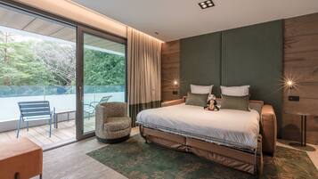 A modern bedroom with a large bed, a seating area with a chair and table, and a view of the outdoors.