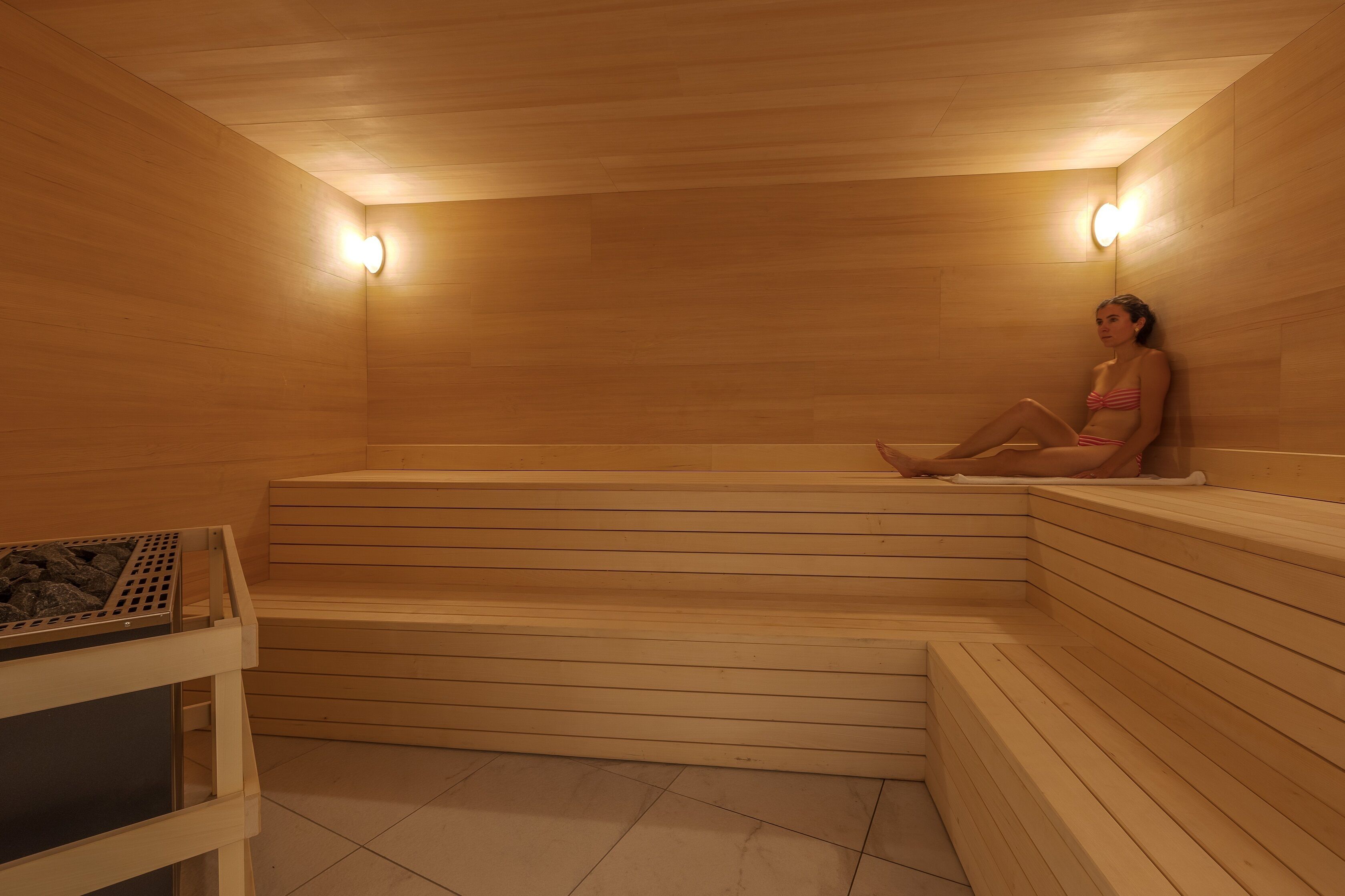 Un sauna avec des bancs en bois et un système de chauffage intégré aux bancs.