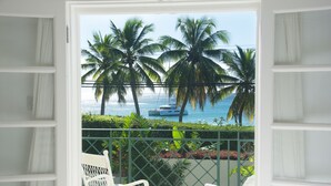 A balcony with white wicker chairs, a view of the ocean, palm trees, and a boat. - Tradewinds, villa with sea views & pool, 1min walk to beach.  (Saint Peter)