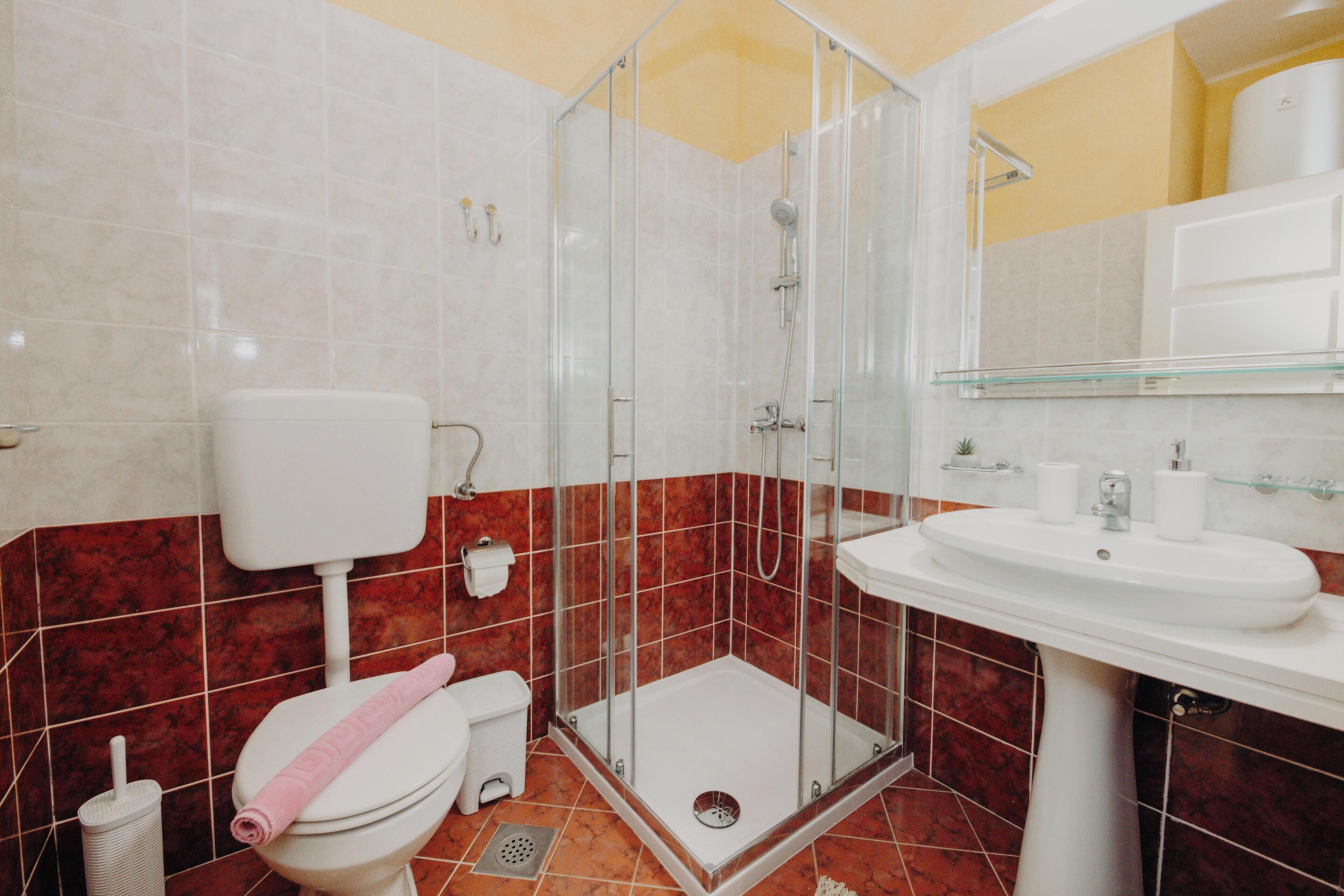 A bathroom with a toilet, shower, sink, and a glass shower enclosure.