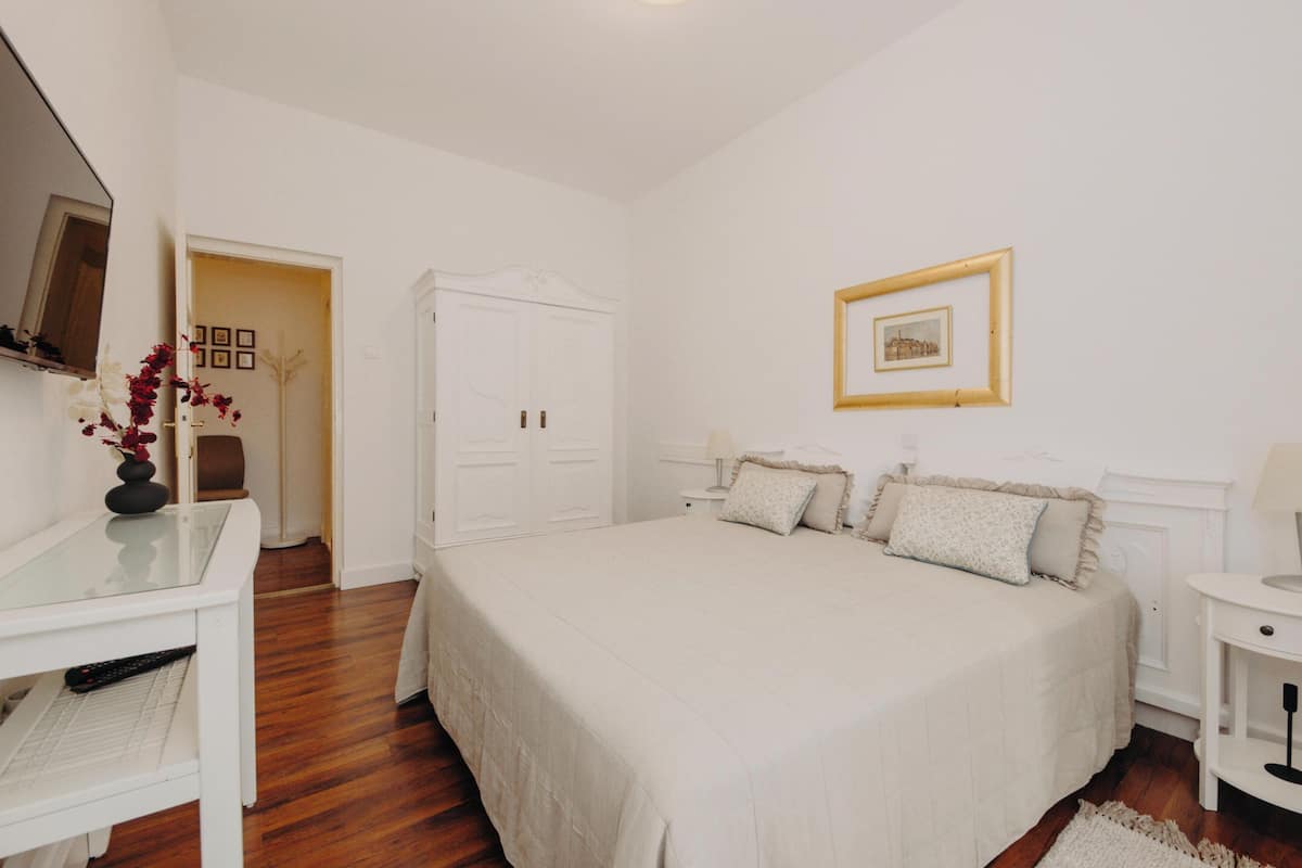 Une chambre à coucher comprenant un lit, des tables de chevet, un bureau, une chaise et une armoire.