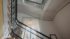Una escalera con barandillas de metal ornamentadas y un techo decorativo.