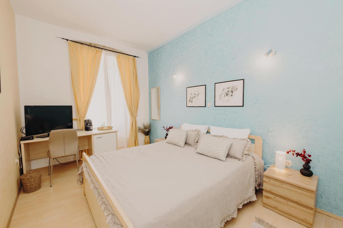 Une chambre à coucher comprenant un lit, un bureau, une télévision et une table de chevet.