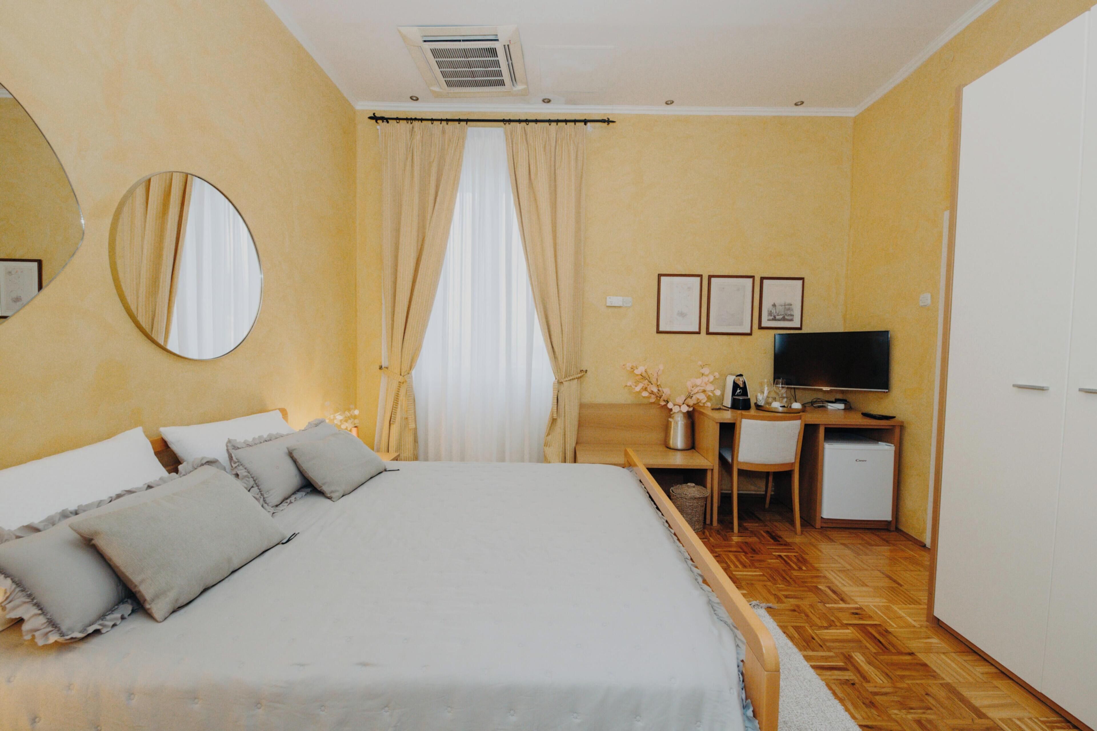A bedroom with a bed, a desk, a television, and a small refrigerator.