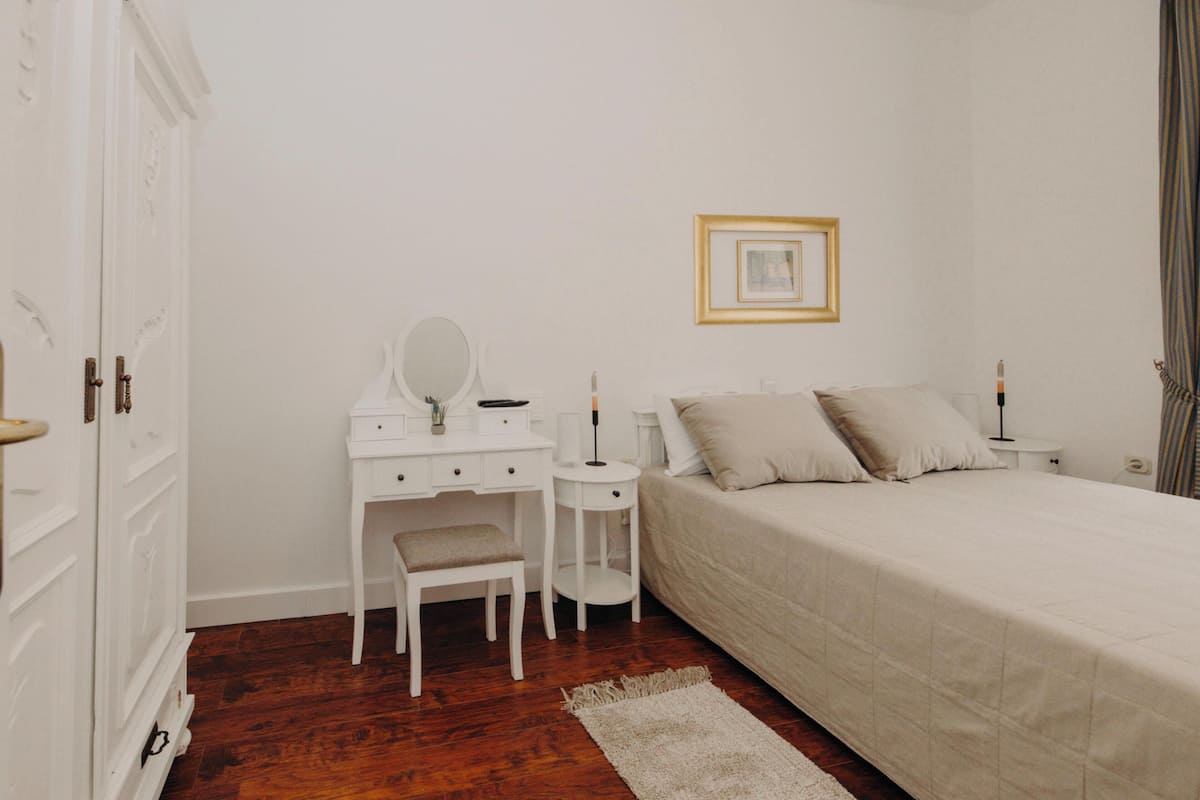 Une chambre à coucher comprenant un lit, un bureau, une chaise, une petite table et un tableau encadré accroché au mur.
