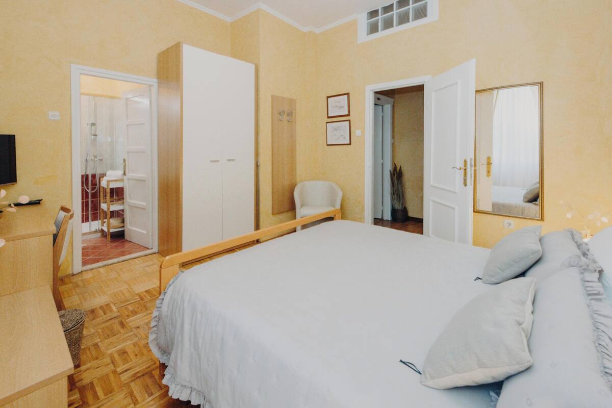 Une chambre avec un grand lit, une armoire, un bureau et un miroir.