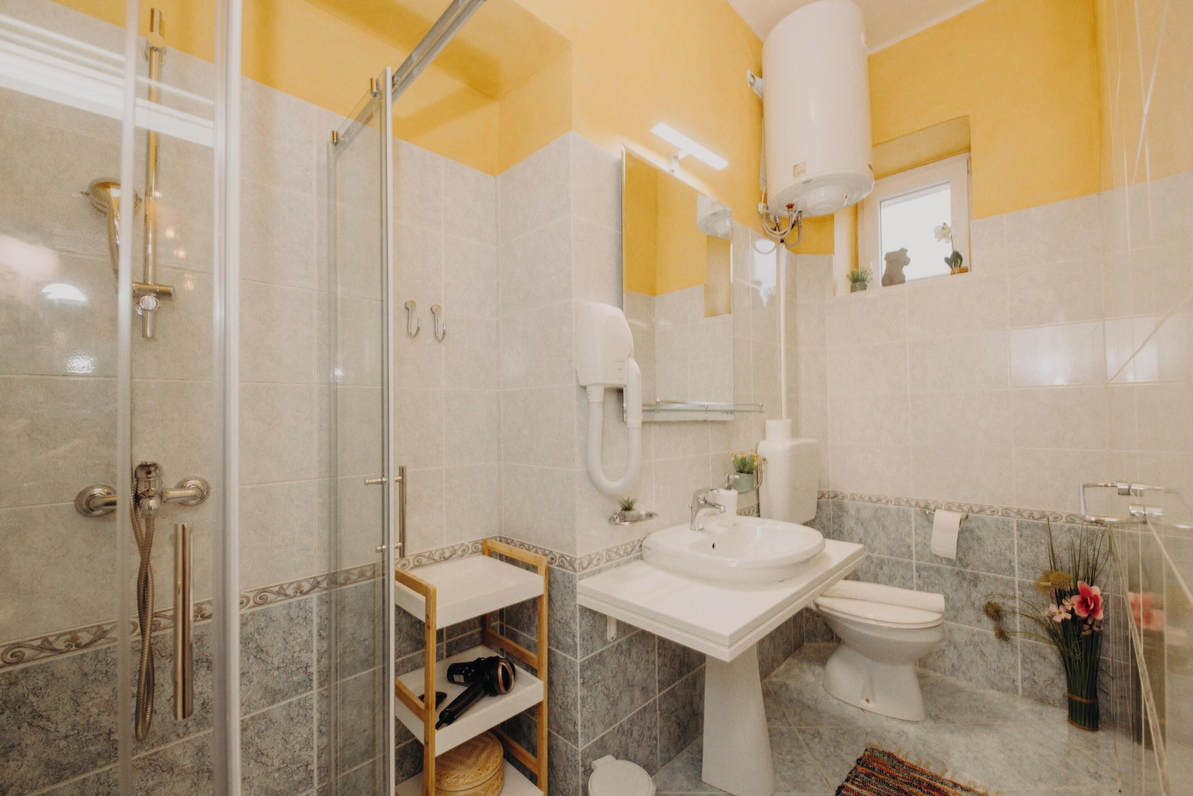 A bathroom with a glass shower enclosure, a sink, a toilet, and a mirror.