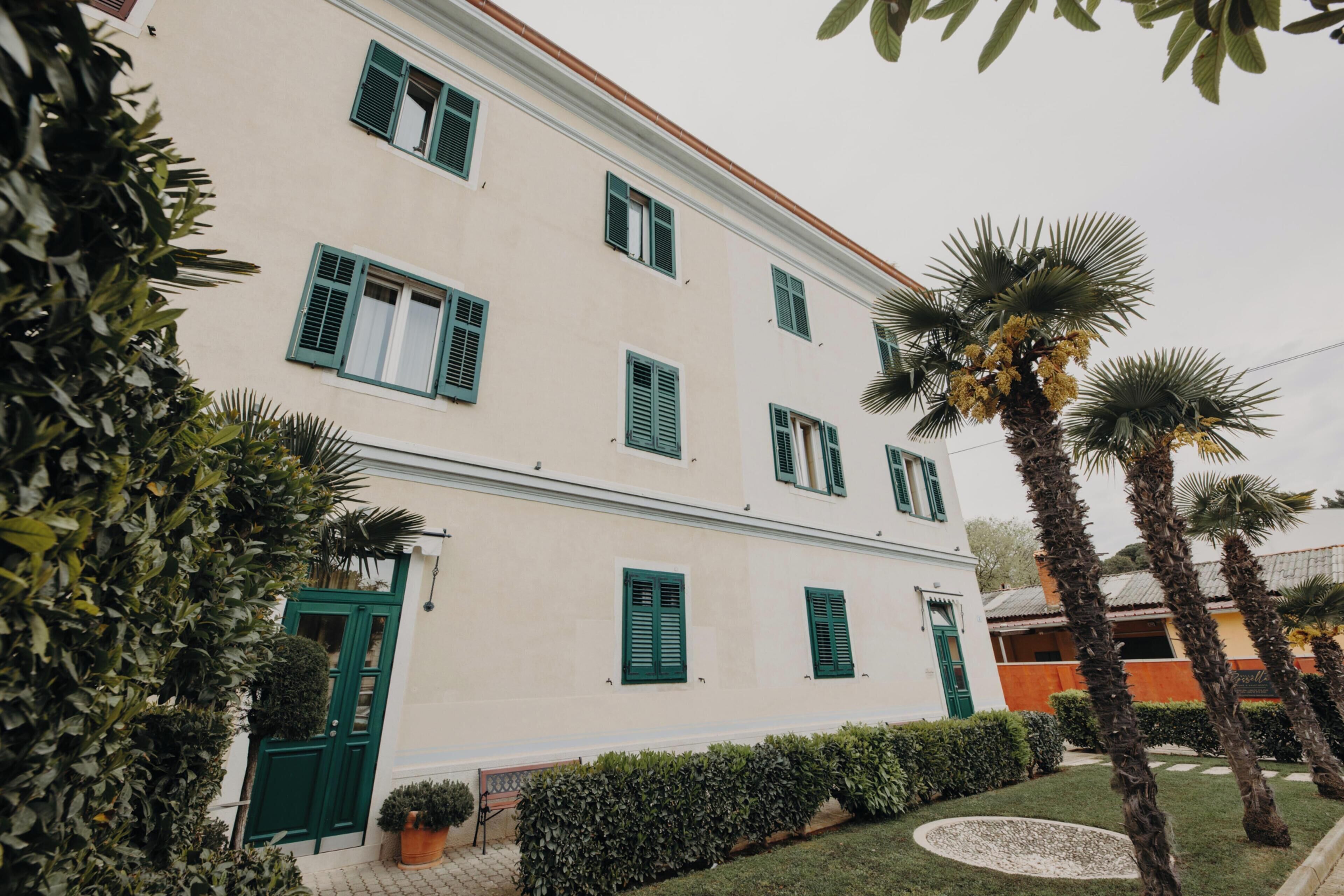 A two-story building with green shutters and a white facade.