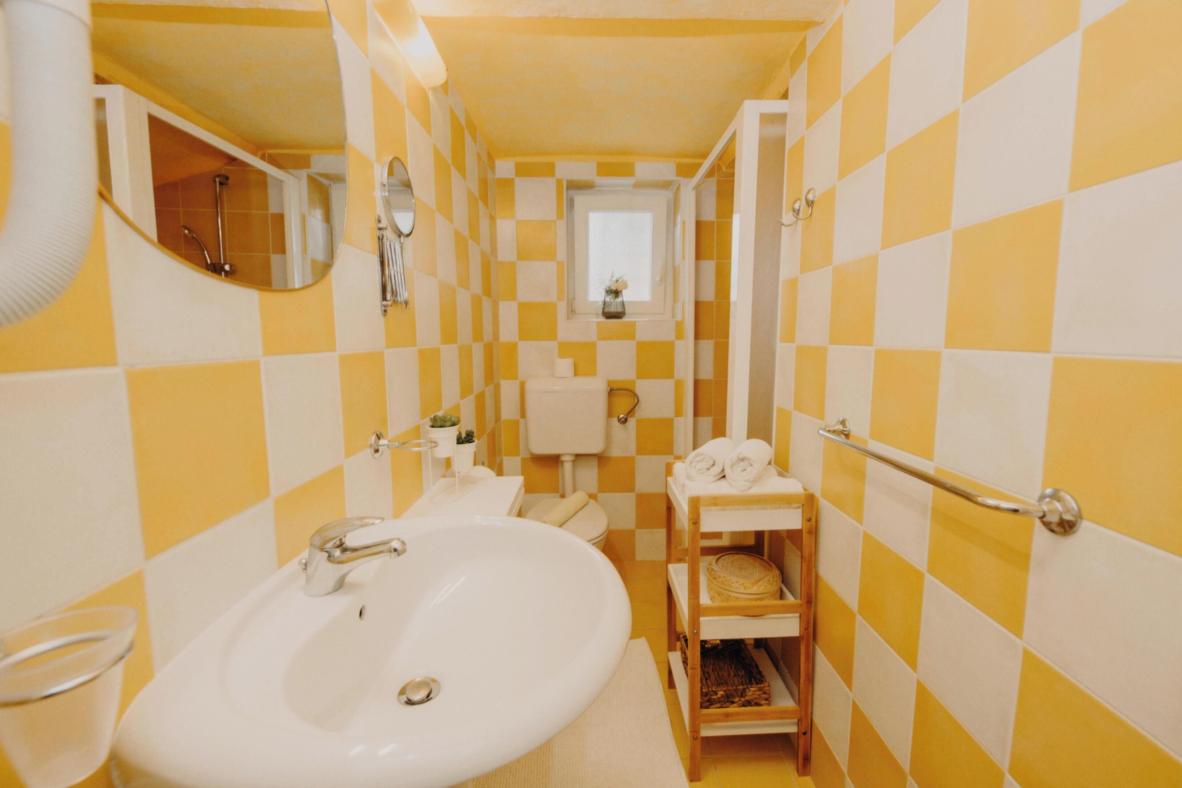 Une salle de bain avec un lavabo blanc, un miroir et un porte-serviettes.