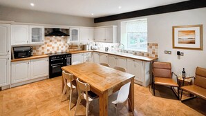 Eine moderne Küche mit weißen Schränken, einem Holztisch und einem eingebauten Backofen.