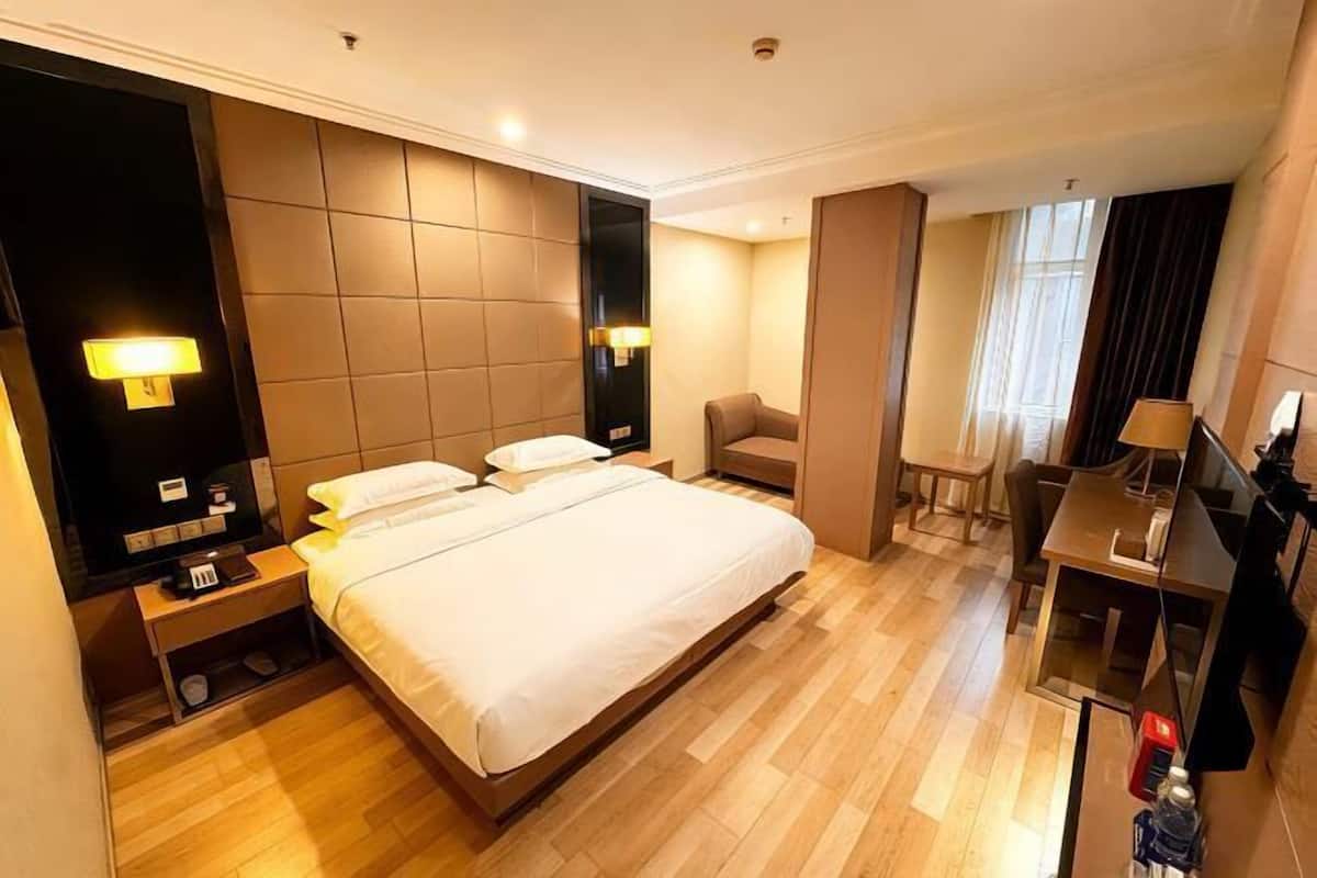 Ein Hotelzimmer mit einem großen Bett, Nachttischen, einem Schreibtisch und einem Sessel.