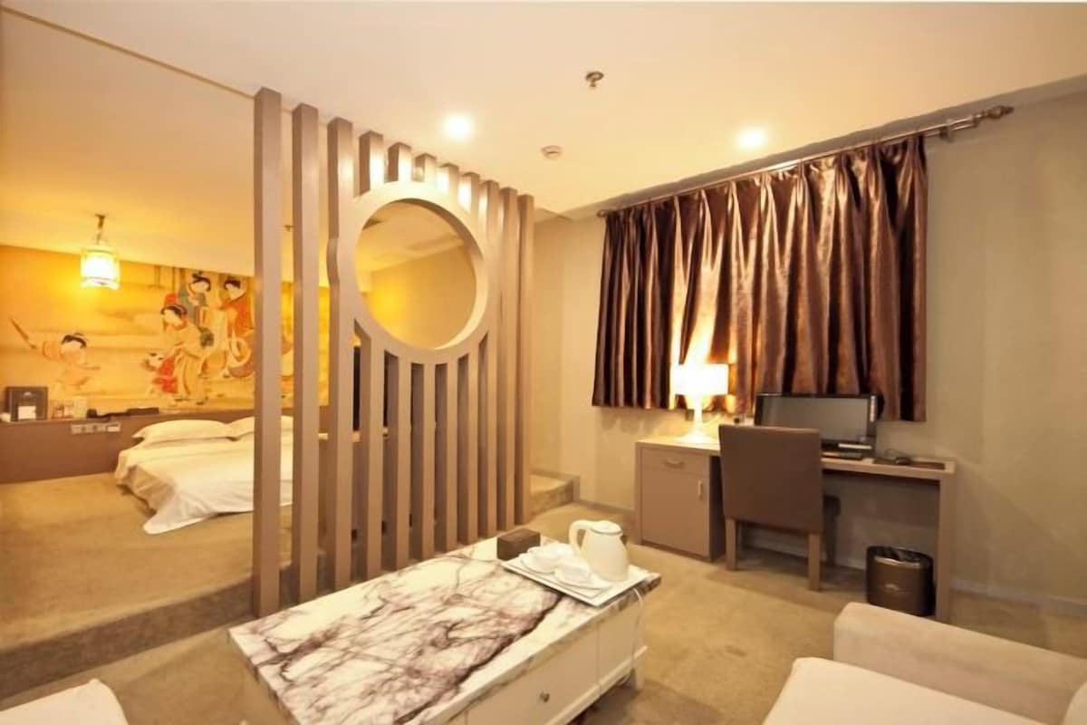 Une chambre d’hôtel équipée d’un lit, d’un bureau, d’un ordinateur, d’une chaise, d’une lampe et d’un miroir décoratif.